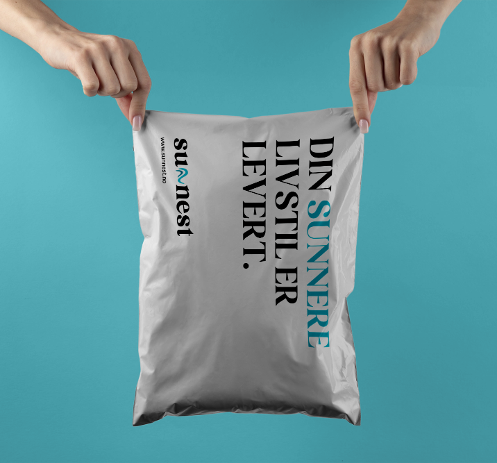 Hender som holder Sunnest sin mailing emballasje, på pakken står det 